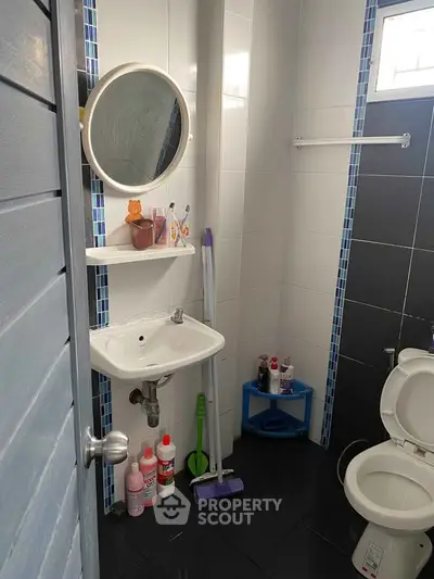 Compact bathroom with modern fixtures and cleaning supplies