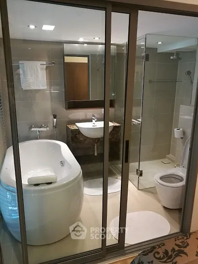 Luxurious modern bathroom with glass shower and elegant bathtub in upscale apartment.