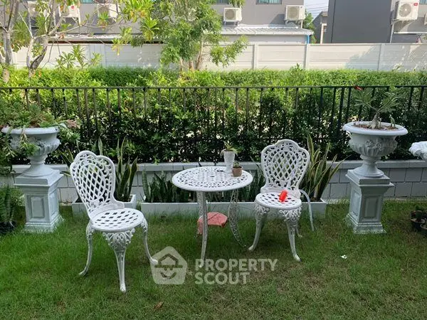 Charming garden with elegant white wrought iron furniture set for relaxing outdoors.