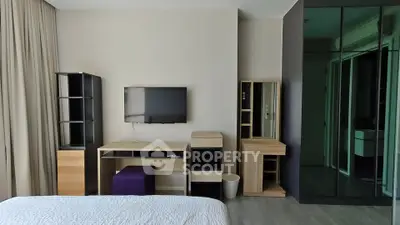 Modern bedroom with sleek furniture and wall-mounted TV in a stylish apartment.
