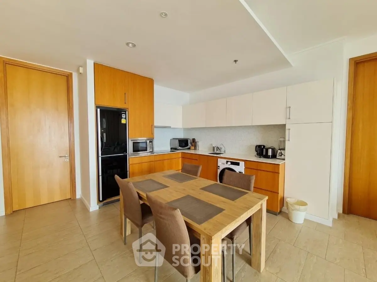 Modern kitchen with wooden cabinets and dining area in open layout apartment.