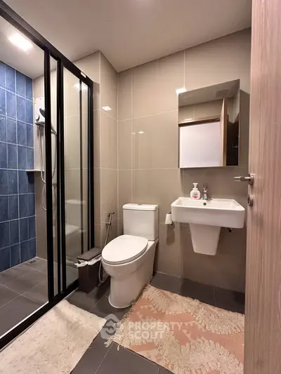 Modern bathroom with sleek design, featuring glass shower enclosure and stylish fixtures.