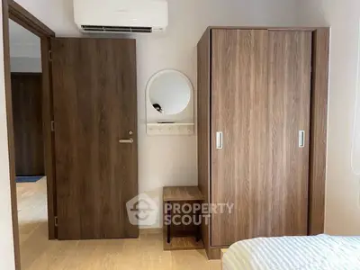 Modern bedroom with wooden wardrobe and air conditioning unit, showcasing minimalist design.