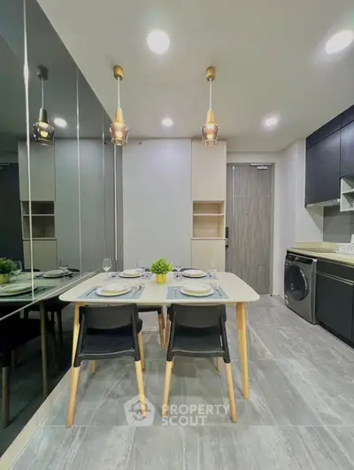 Modern kitchen with dining area, sleek cabinetry, and stylish lighting in a contemporary apartment.