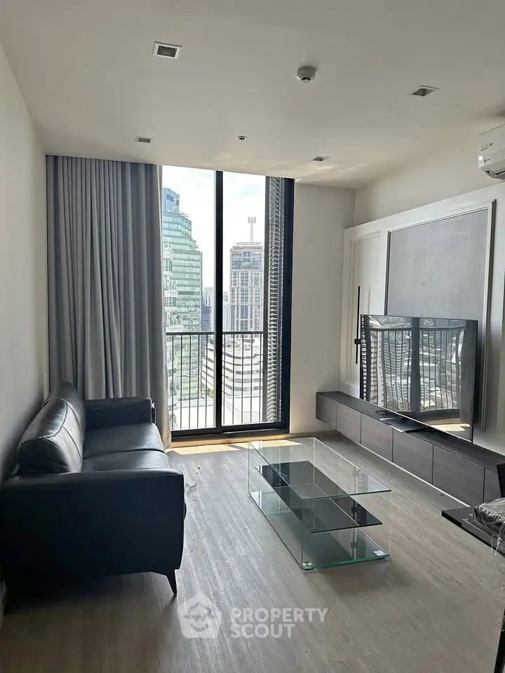 Modern living room with city view, sleek furniture, and large window for natural light.