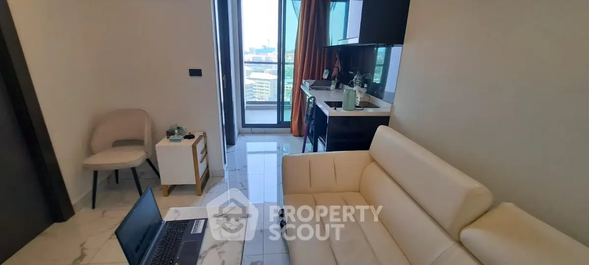 Modern living room with elegant cream sofa, marble flooring, and access to a sunlit balcony with a view, perfect for urban living.