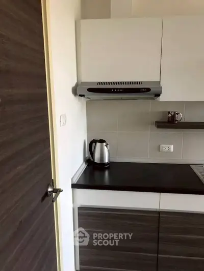 Modern kitchen with sleek cabinets and electric kettle, ideal for compact living spaces.