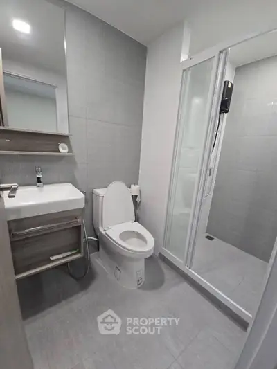 Modern bathroom with sleek design, featuring a shower, toilet, and sink in a contemporary setting.