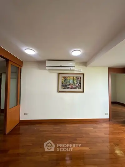 Spacious living room with wooden flooring and modern air conditioning unit.