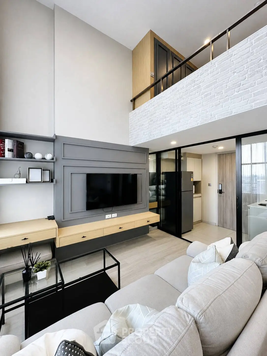 Modern living room with high ceiling and mezzanine, featuring sleek furniture and built-in storage.