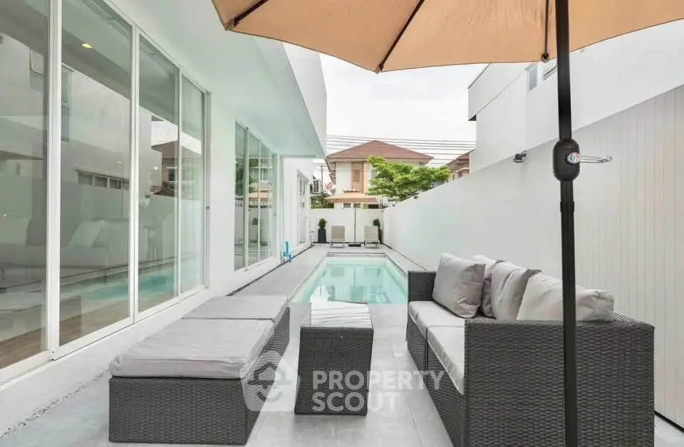 Modern outdoor patio with pool and stylish seating in a contemporary home setting.