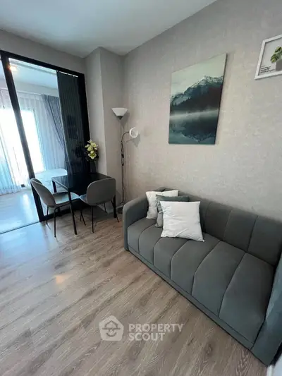 Modern living room with sleek gray sofa and elegant decor, adjacent to a cozy dining area.