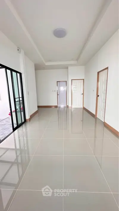 Spacious modern living room with glossy tiled floors and sliding glass doors.