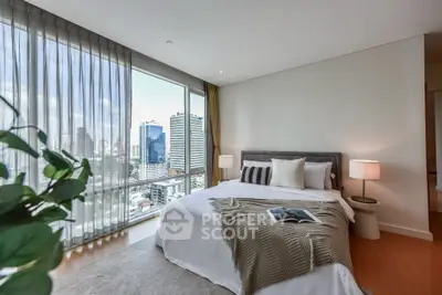 Luxurious bedroom with city view and modern decor in high-rise apartment.