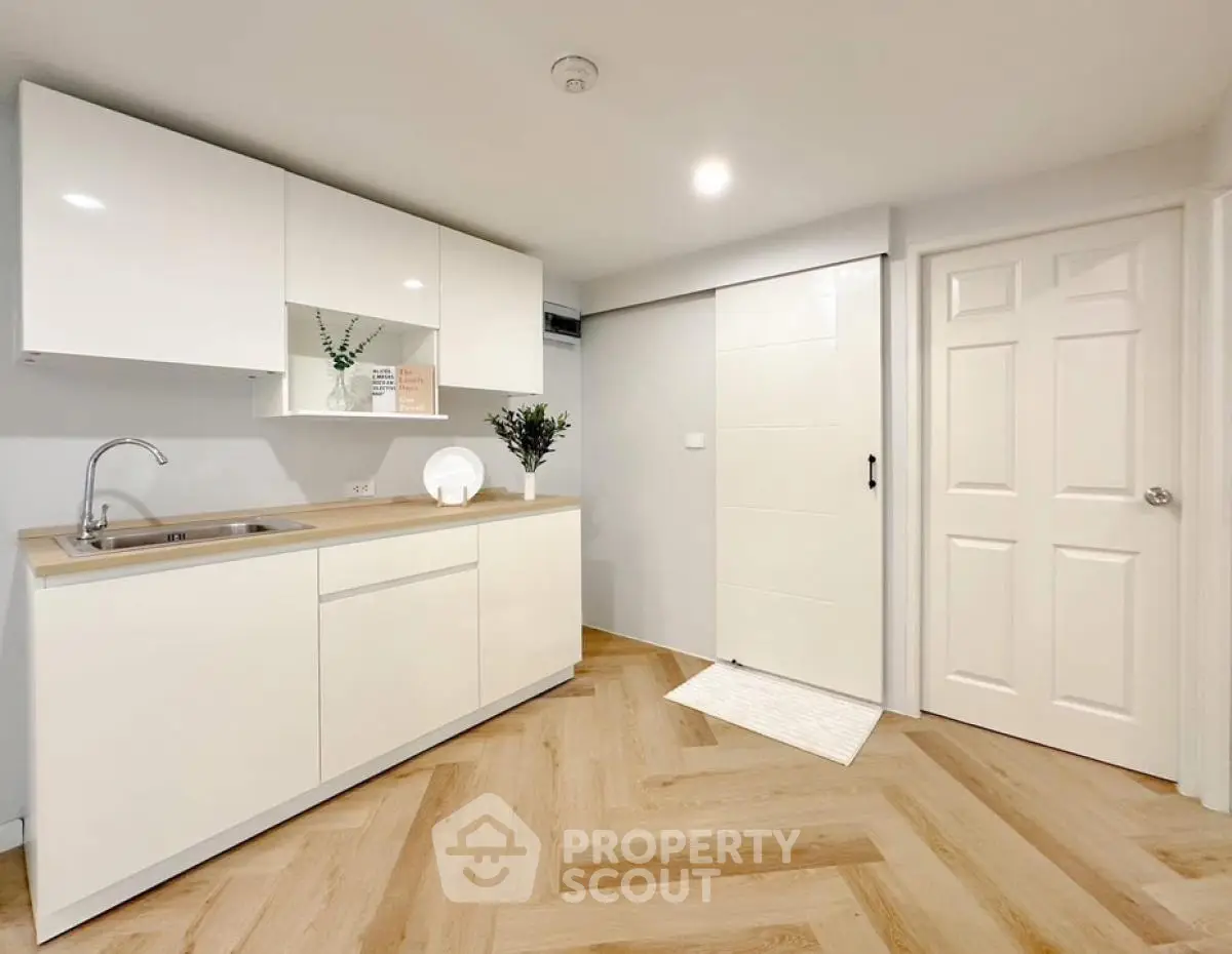 Modern minimalist kitchen with sleek white cabinets and wood flooring
