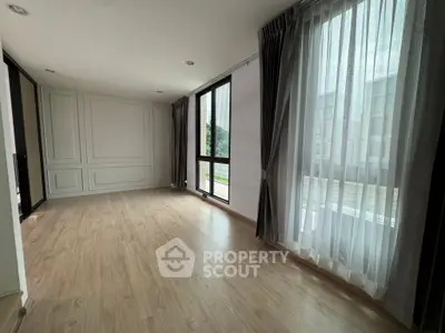 Spacious empty room with large windows and wooden flooring, perfect for customization.