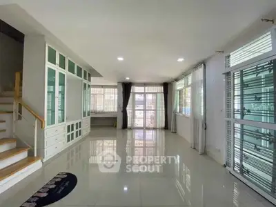 Spacious modern living room with large windows and elegant staircase