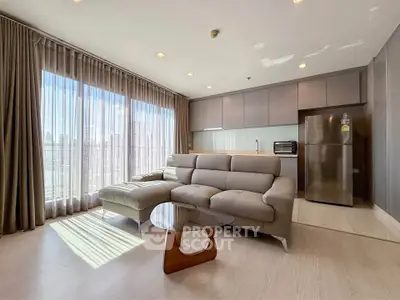 Spacious modern living room with large windows and sleek kitchen area in a high-rise apartment.