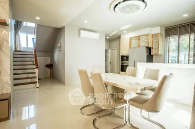 Luxurious open-plan dining area with modern kitchen and elegant staircase
