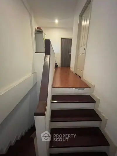 Charming interior hallway with wooden stairs and modern doors, perfect for cozy living.