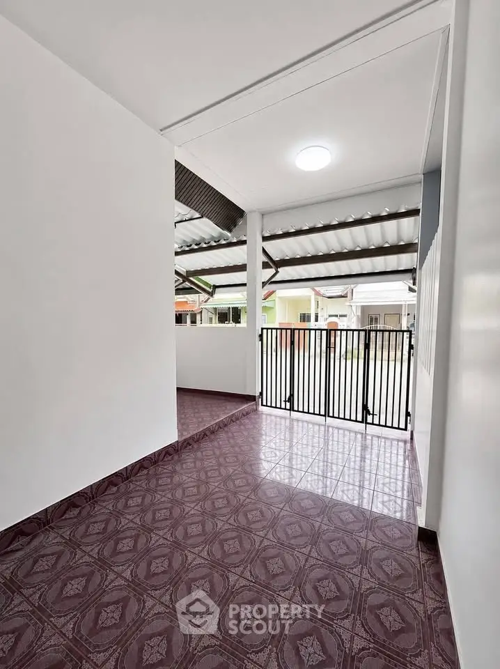 Spacious covered balcony with patterned tile flooring and modern railing, perfect for outdoor relaxation.