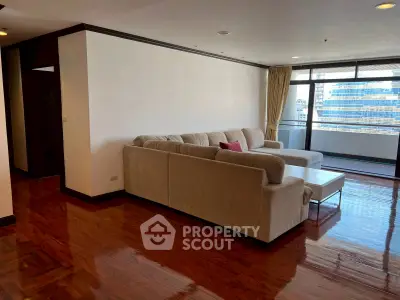 Spacious living room with elegant wooden flooring and large windows offering city views.