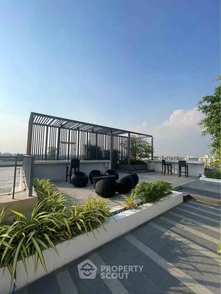 Stunning rooftop terrace with modern seating and lush greenery under a clear blue sky.