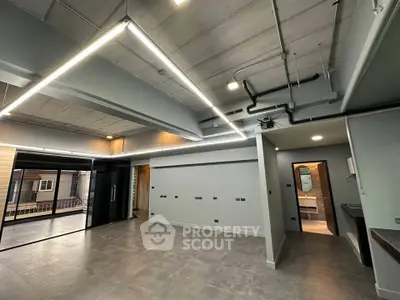 Modern industrial-style living room with exposed ceiling and sleek lighting