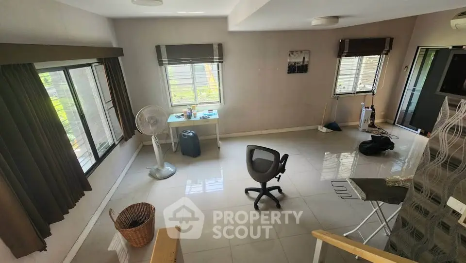 Spacious room with large windows and modern furnishings, ideal for versatile living or office space.