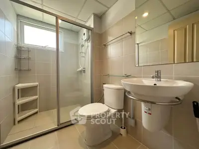 Modern bathroom with glass shower, sleek fixtures, and neutral tiles.