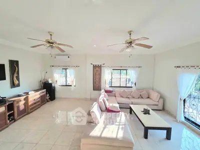 Spacious living room with elegant decor and natural light, featuring ceiling fans and comfortable seating.