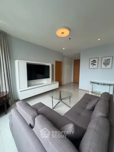 Modern living room with sleek furniture and wall-mounted TV in a bright apartment.