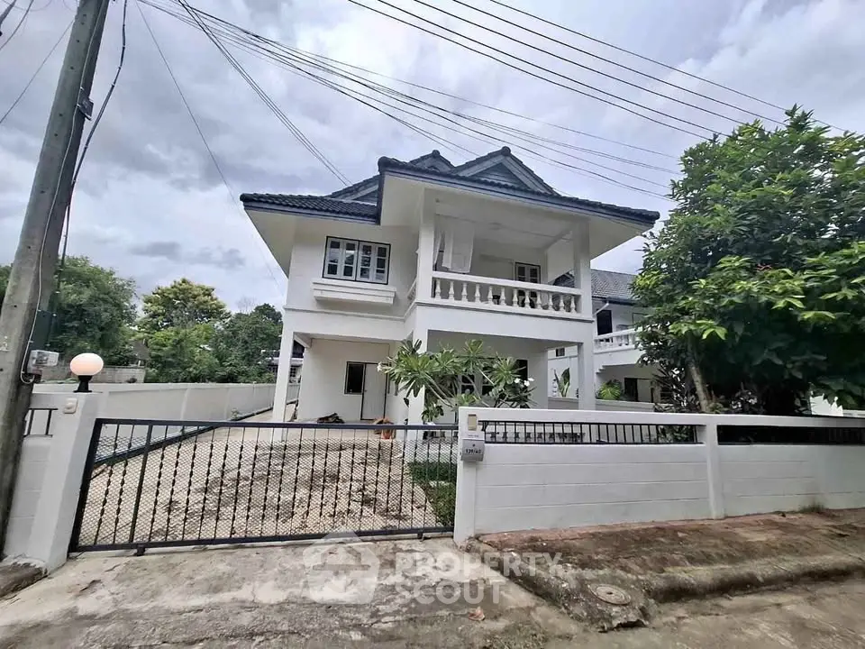 Charming two-story white house with spacious driveway and lush greenery, perfect for family living.