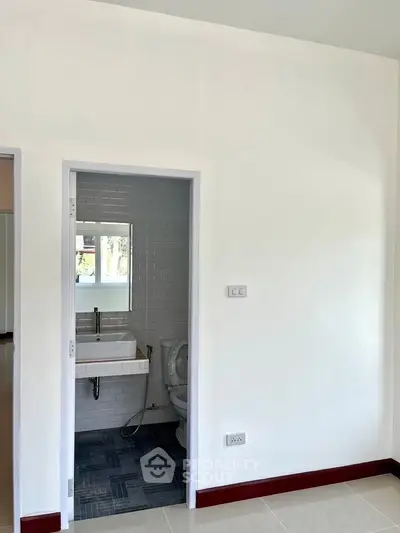 Minimalist bathroom with modern sink and toilet in a bright, white interior.