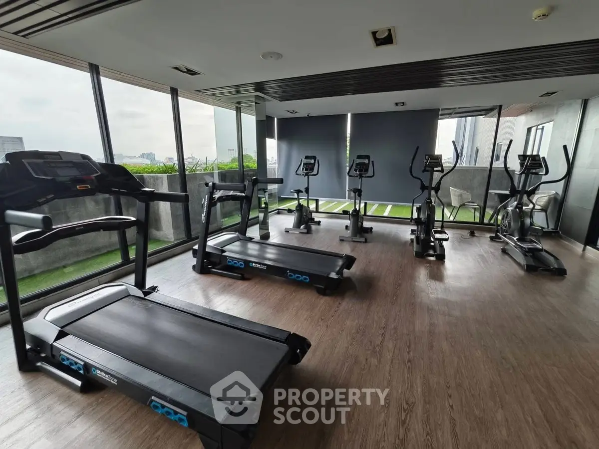 Modern gym with city view, featuring state-of-the-art exercise equipment and floor-to-ceiling windows.