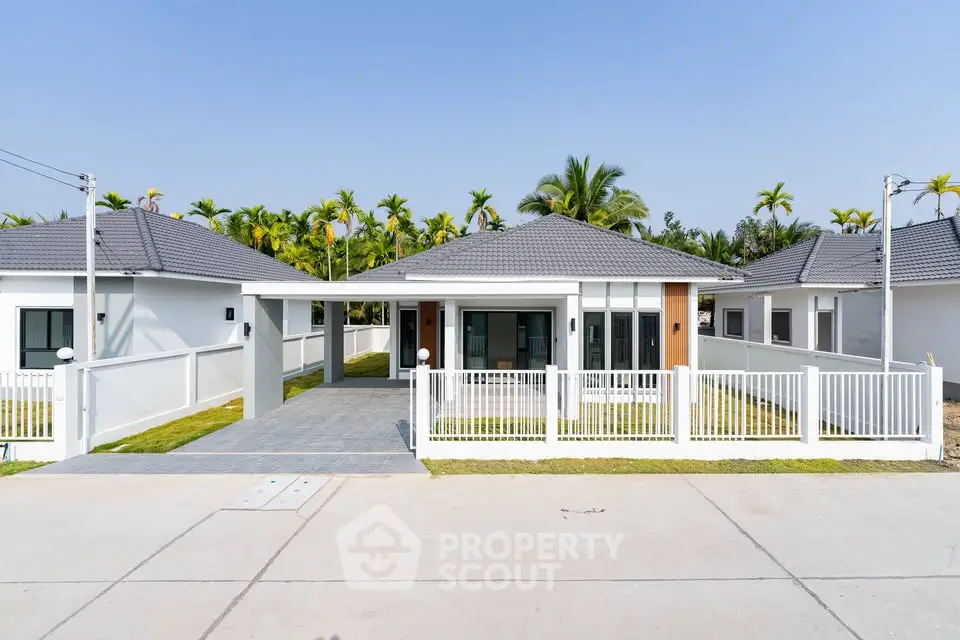 Modern single-story home with spacious driveway and tropical landscaping.