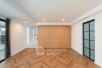 Spacious modern living room with herringbone wood flooring and stylish wall paneling.