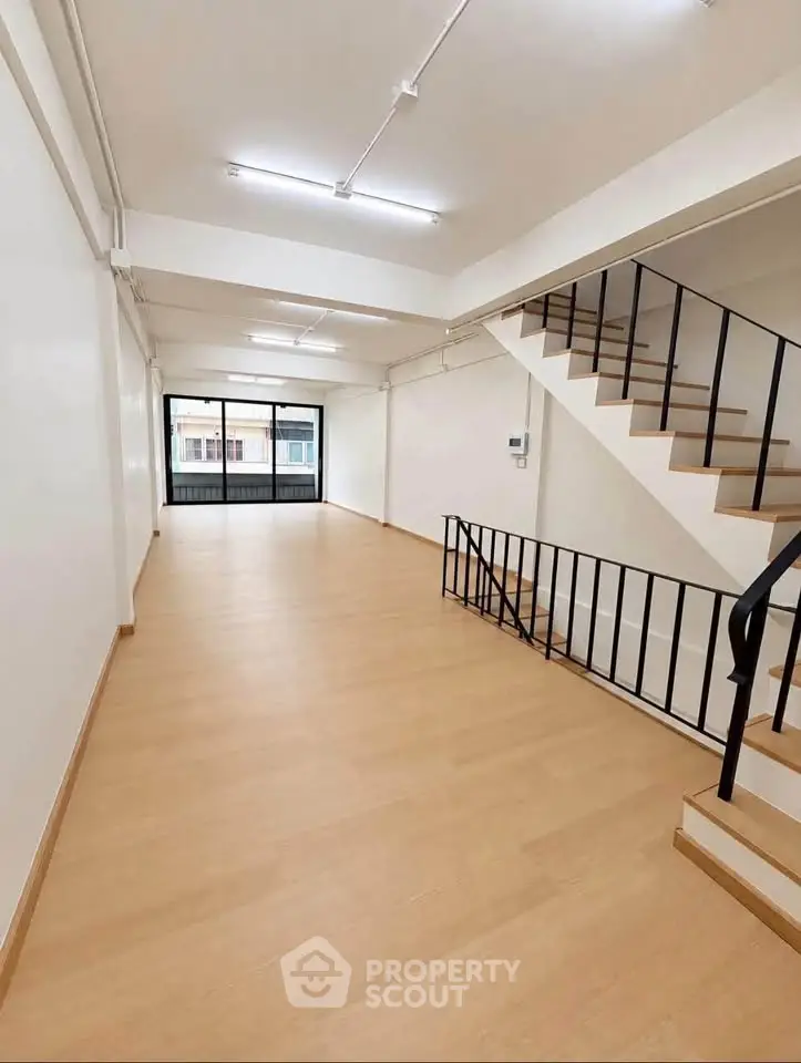 Spacious open-plan interior with modern staircase and large windows.