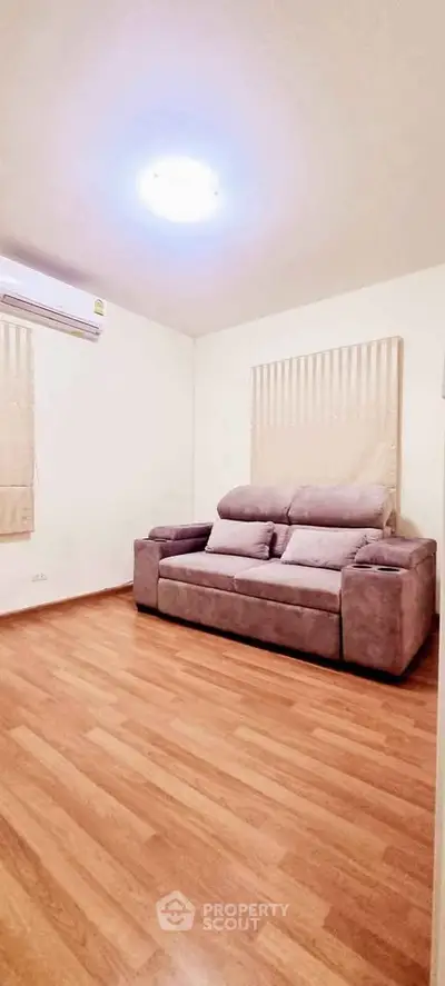 Cozy living room with wooden flooring and comfortable sofa, perfect for relaxation.