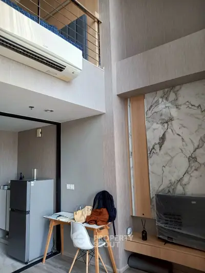 Modern loft apartment with stylish interior, featuring a marble accent wall and compact kitchen area.