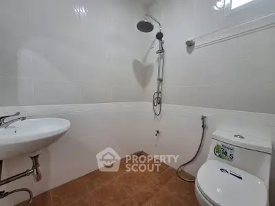 Modern bathroom with white tiles, shower, and toilet in a real estate property.