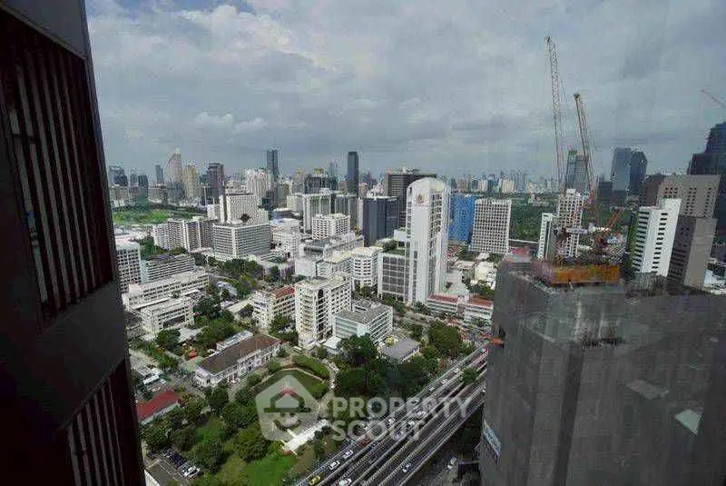 Stunning cityscape view from high-rise building showcasing urban skyline and construction cranes.