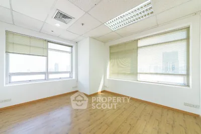 Spacious empty room with large windows and wooden flooring in modern building