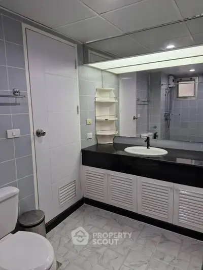 Modern bathroom with sleek fixtures and large mirror in a stylish real estate property.