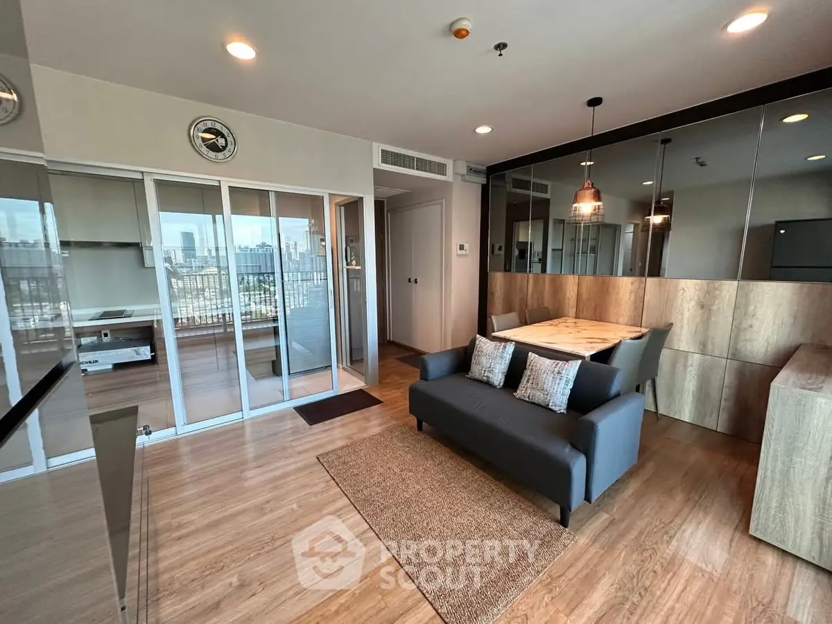 Modern living room with glass doors and city view, featuring stylish decor and ample natural light.