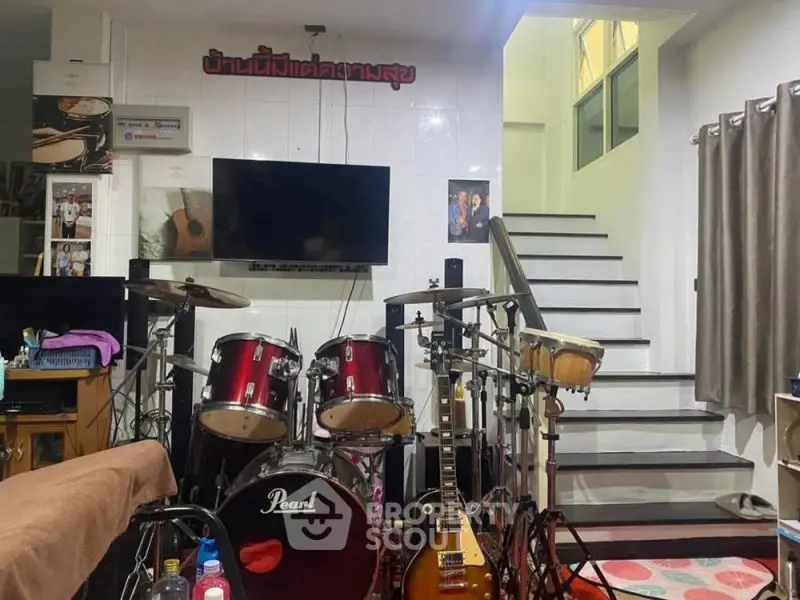 Cozy music-themed living area with drum set and guitar, perfect for musicians.