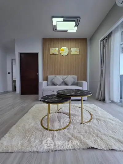 Modern living room with stylish decor and cozy seating area, featuring elegant coffee tables and plush rug.