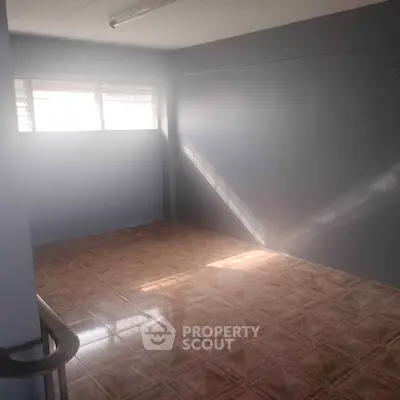Spacious empty room with tiled floor and natural light, perfect for customization.