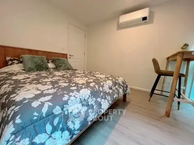 Cozy bedroom with floral bedding and modern decor, featuring air conditioning and a stylish desk area.