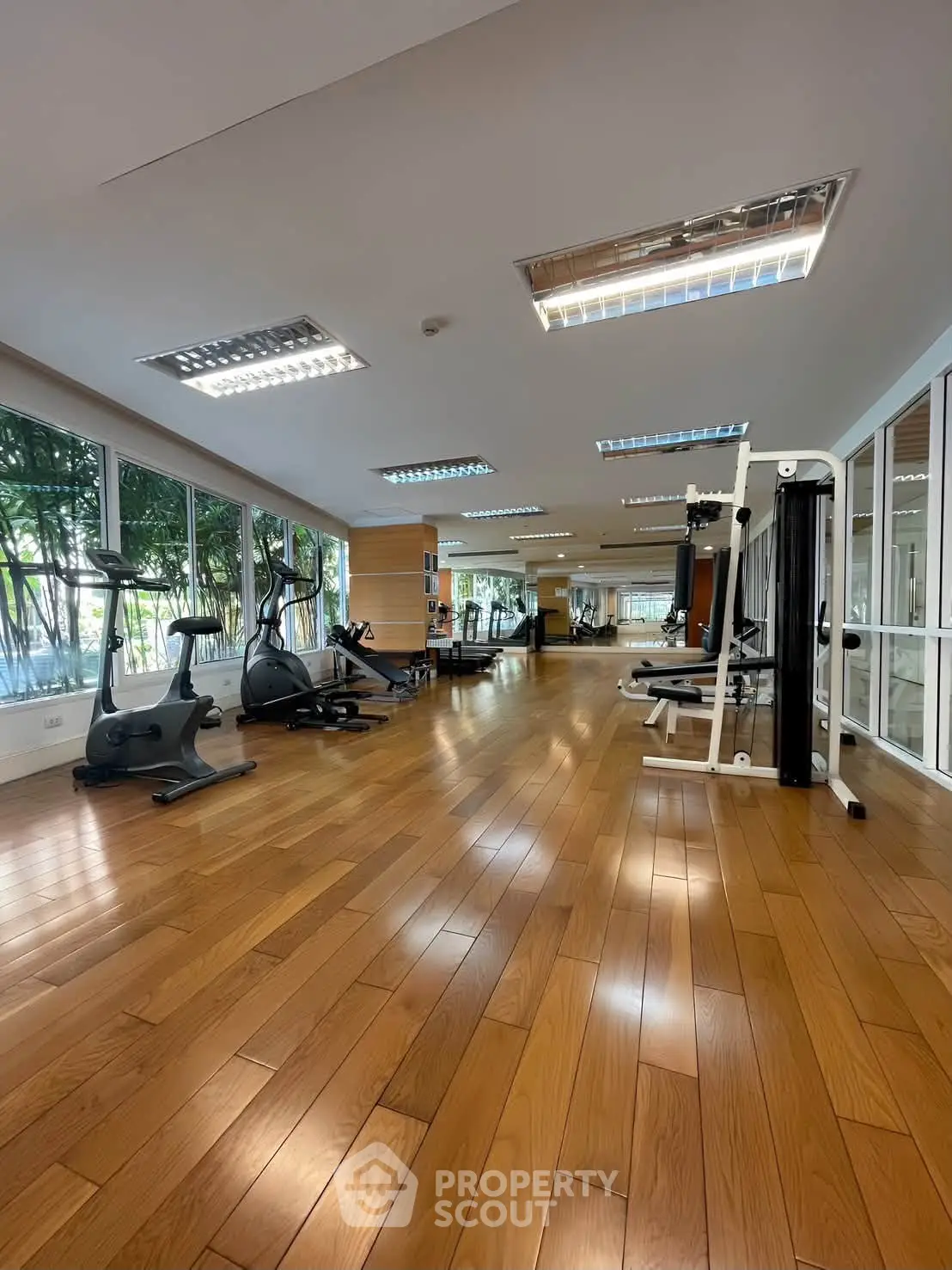 Spacious gym with modern equipment and wooden flooring in a luxury residential building.
